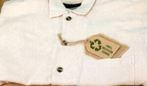 Recycle clothes icon on label with 100 Recycled fabric text. Sustainable fashion and ethical shopping conscious consumerism concept