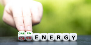 Hand turns dice and changes the expression "fossil energy" to "green energy".