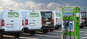 Electric vehicles charging station on a background of a row of vans. Green transportation concept