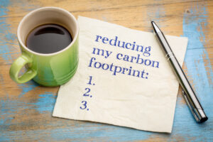 reducing my carbon footprint list - handwriting on a napkin with a cup of espresso coffee