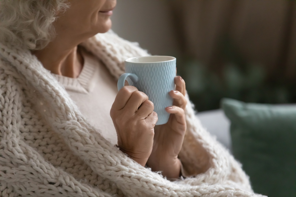 person wrapped up in blanket with a cuppa