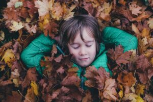 child lying amongst leaves