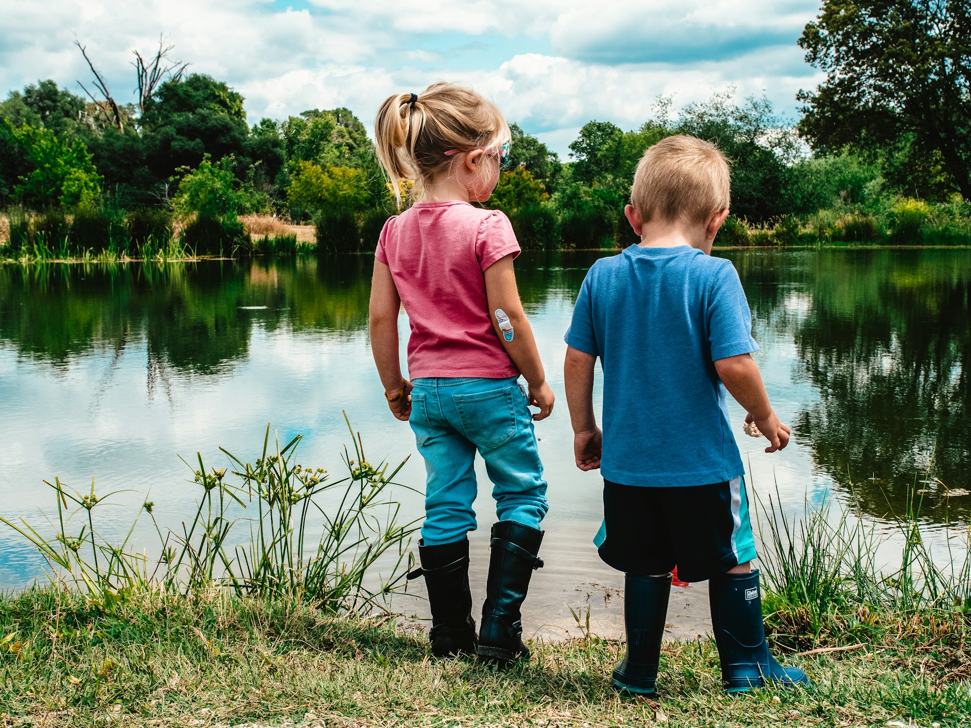 two children looking down on a pond
