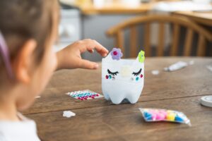 Girl Doing Crafts With Plastic Bottle And Paints.