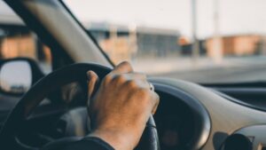 hand on steering wheel driving a car